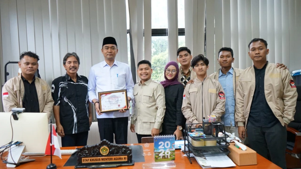 Staf Khusus Menteri Agama Gugun Gumilar memegang plakat bersama Sekjen DPP GEMPITA Yukenriusman Hulu dan pengurus DPP GEMPITA di ruang kerjanya
